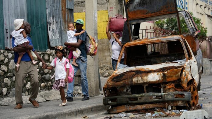 Residents walk past a burnt car as they evacuate a neighbourhood due to gang violence in Port-au-Prince, Haiti, May 2, 2024. (AP Photo/Ramon Espinosa)
