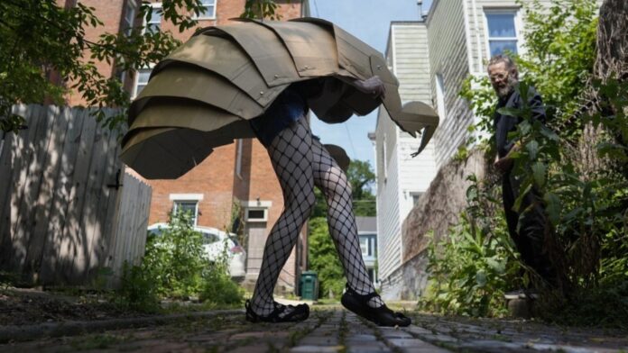Renee Martin performs her cicada striptease in fishnet stockings and a cicada nymph puppet costume in a Cincinnati ally on Tuesday, June 4, 2024. (AP Photo/Carolyn Kaster)
