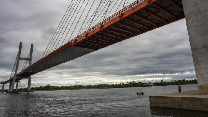 A youth jumps off the footing of a bridge that is part of a federal highway project, extending over the Nanay River in Iquitos, Peru, Tuesday, May 28, 2024. (Rodrigo Abd/AP Photo)