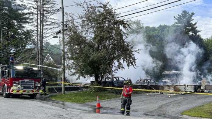 Auburn firefighters hose down the remains of home in Auburn, Maine, early Saturday, June 15, 2024. Police have canceled a shelter-in-place order in the city after reporting that an armed person was in an area where a series of explosions and a house fire erupted early Saturday. (Russ Dillingham/Sun Journal via AP)